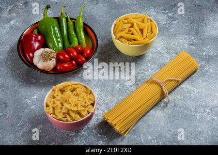 Spaghetti crudi con verdure su sfondo marmoreo Foto Stock