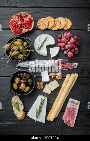 Tavolo per antipasti con diversi antipasti, su tavolo in legno nero, piatto Foto Stock
