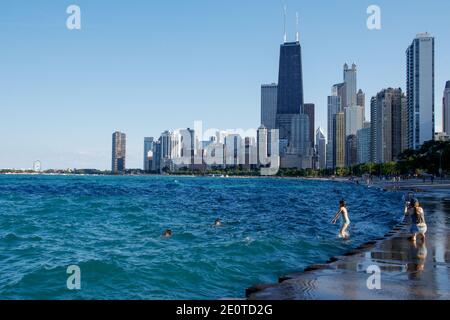 Fronte lago di Chicago vicino a North Avenue Beach. Giovane donna che salta dal muro di mare al lago. Foto Stock