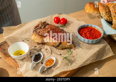 Una vista ravvicinata della bistecca che serve su un tavolo da cucina in legno, mentre sui lati ci sono piatti laterali come verdure e spezie in piccole ciotole. Foto Stock