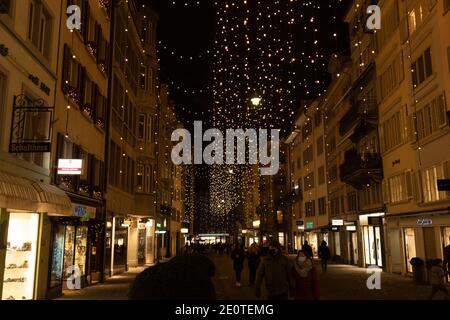 Shopping natalizio sotto le tradizionali luci natalizie chiamato Lucy in Rennweg, una strada laterale di Bahnhofstrasse a Zurigo. Edifici pedonali e antichi Foto Stock