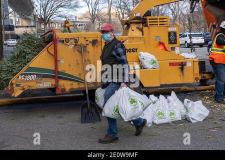 EW YORK, NY – 2 GENNAIO: Un uomo trasporta i sacchetti di pacciame di alberi durante il Mulchfest di New York City all'Astoria Park il 2 gennaio 2021 a New York City. I newyorkesi possono portare il loro albero e un sacchetto della tote ad un luogo di scheggiatura e guardare il loro albero che è scheggiato, quindi portare il loro proprio pacciame nutriente-ricco a casa con loro. Parchi e DSNY hanno raccolto e mulched alberi per aiutare a piantare letti e giardini comunitari intorno alla città crescere. Credit: Ron Adar/Alamy Live News Foto Stock