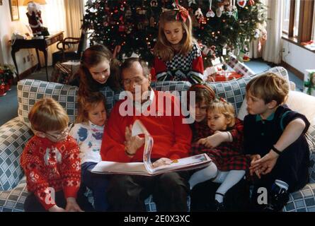 Camp David, Maryland - 24 dicembre 1991 -- Presidente degli Stati Uniti George H.W. Bush legge una storia di Natale ai suoi nipoti, Pierce Bush, Marshall Bush, Barbara Bush (figlia di George W. Bush), Lauren Bush, Jenna Bush (figlia di George W. Bush), Ashley Bush e Sam Lebiond a Camp David nel Maryland la vigilia di Natale, 24 dicembre 1991. Foto di Casa Bianca via CNP/ABACAPRESS.COM Foto Stock