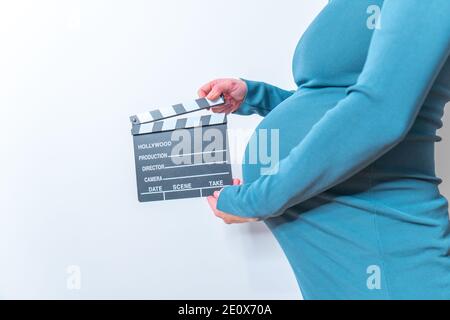 Donna incinta mani battaglio board sul suo ventre Foto Stock