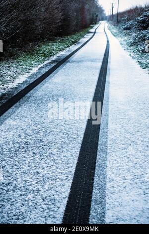 Black Tire si insegue nella neve fresca su un rettilineo lungo stretta corsia di campagna Foto Stock
