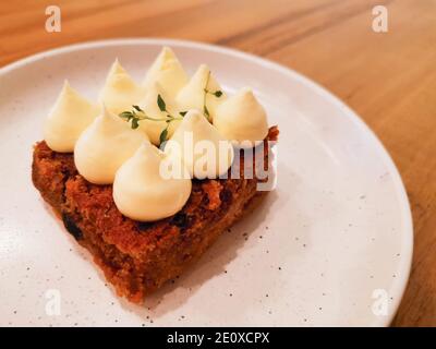 Torta di carote con formaggio cremoso su un piatto bianco. Dessert in una caffetteria. Foto Stock