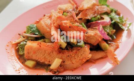 Maiale alla griglia a fette sottili. Insalata tailandese speziata con peperoncino in polvere arrosto, riso arrosto macinato e succo di limone. Foto Stock