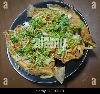 Pesce fritto con insalata piccante aggiungere peperoncini freschi tritati, scalogni tagliati, placcatura tagliata grossolanamente e coriandolo tritato. Foto Stock