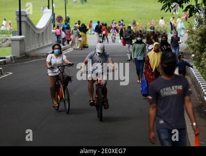 Bogor, Indonesia. 02 gennaio 2021. I visitatori che indossano maschere facciali che cavalcano una bicicletta sono visti al Giardino Botanico di Bogor, Giava Occidentale, durante la festa di Capodanno in Indonesia, il 2 gennaio 2021. (Foto di Adriana/INA Photo Agency/Sipa USA) Credit: Sipa USA/Alamy Live News Foto Stock