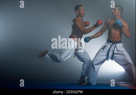 Giovane di mettere in pratica il suo karate si muove, bianco kimono e cintura nera Foto Stock