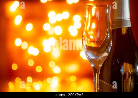 Bicchiere di champagne vuoto e bottiglia di spumante o champagne con sfondo a lume di candela in un ambiente romantico. Foto Stock