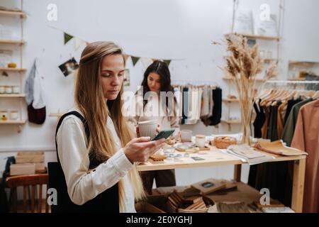 Donna impegnata in piedi in un negozio ecologico che guarda il telefono in mano Foto Stock