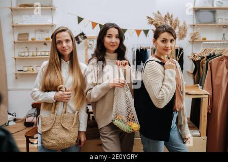 Tre donne in ecological shop in posa con diverse eco borse Foto Stock