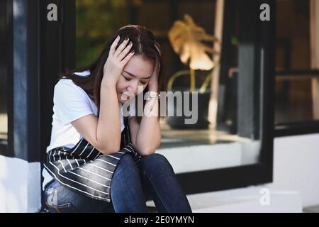 Giovane donna che indossa grembiule cameriera sensazione di soffrire di disperato e stressato. Foto Stock