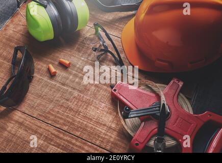 Nastro tecnico misura i guanti di sicurezza casco di protezione dell'orecchio su tavola di legno. Foto Stock