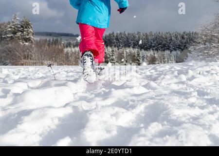 Bambino che corre nella neve, scarpe invernali nella neve. Foto Stock