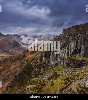 Epico drone volante immagine del paesaggio di Langdale Pikes e valle In inverno con nuvole a basso livello e nebbia che rotolano intorno Foto Stock