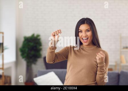 Donna eccitata che festeggia l'acquisto della sua propria casa o appartamento e. visualizzazione dei tasti Foto Stock
