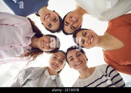 Gruppo di belle donne felici che si levano insieme in cerchio e. sorridendo alla macchina fotografica Foto Stock
