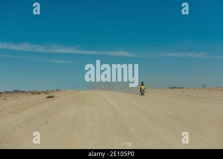 Motociclista su una strada sporca nel deserto del Namibia, Namibia Foto Stock