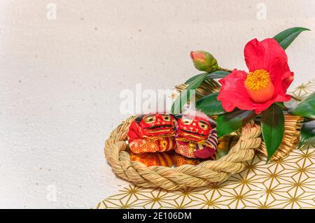 Biglietto d'auguri con un fiore rosso di Tsubaki o una camelia chiamata Rosa invernale e due adorabili figurine di leoni giapponesi Shishi festeggiamo il nuovo anno in Foto Stock