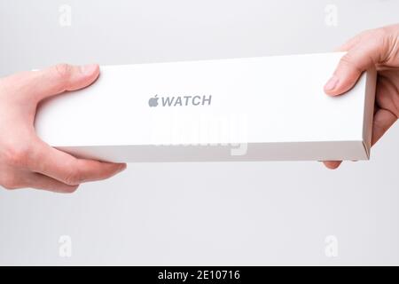 Mano uomo e donna che tiene una scatola con orologio Apple su sfondo grigio, dicembre 2020, San Francisco, Stati Uniti Foto Stock