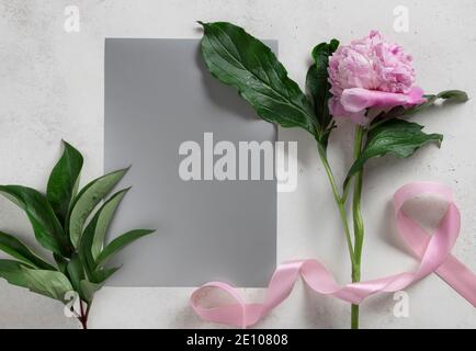 una sola delicata pietra rosa, nastro rosa e carta bianca argentata Foto Stock