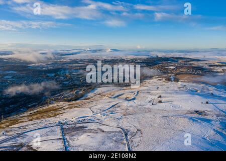 Vista aerea dei droni delle montagne innevate e delle città che si innalzano sopra le valli sud-orientali, Galles Foto Stock