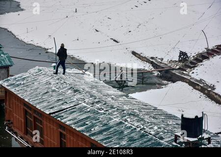 Srinagar, India. 3 gennaio 2021. Un uomo libera la neve dalla sua casa galleggiante dopo una fresca nevicata a Srinagar. Nevicate da moderate a pesanti iniziarono la domenica attraverso la valle del Kashmir tagliando la superficie della valle e il collegamento aereo con il resto del mondo, hanno detto i funzionari. L'uomo delle condizioni atmosferiche ha previsto una caduta di neve diffusa fino al 6 dicembre. Credit: SOPA Images Limited/Alamy Live News Foto Stock