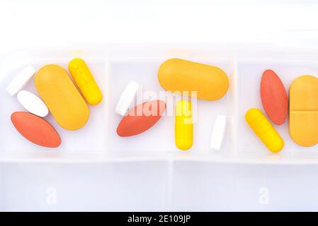 Scatola aperta con pillole gialle, rosse sul tavolo bianco Foto Stock