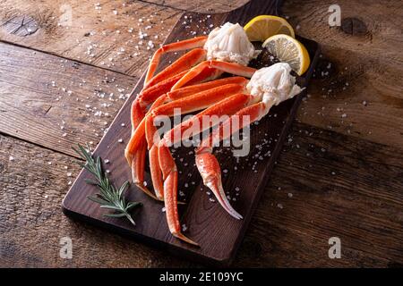 Delizioso grappolo di zampe di granchio di neve su un rustico piano di legno. Foto Stock