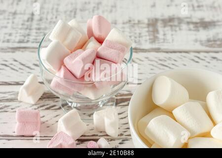 Marshmallow rosa e bianco assortiti in bicchieri su sfondo di legno. Marshmallow a forma di cuore per cioccolata calda o cacao. Foto Stock