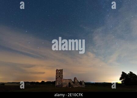 Una foto notturna della chiesa di Knowlton a Dorset, Inghilterra, Regno Unito in una notte parzialmente nuvolosa, con la chiesa illuminata Foto Stock