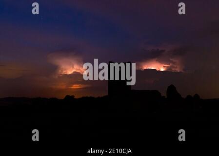 Una foto notturna della chiesa di Knowlton a Dorset, Inghilterra, Regno Unito in una notte nuvolosa con una tempesta elettrica che infuria dietro la chiesa Foto Stock