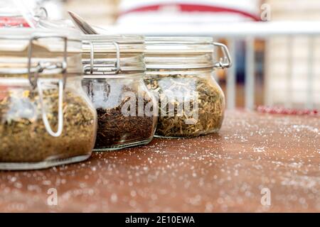 Vasetti con tre diversi tipi di tè sono sul tavolo, medicina alternativa e cibo naturale. Il tè in forma secca, per la preparazione, viene conservato in vasetti di vetro. Foto Stock