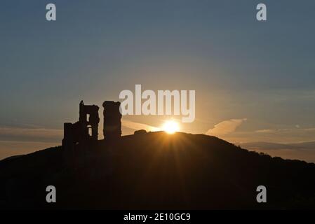 Alba dietro le rovine del castello medievale di Corfe nell'isola di Purbeck, Dorset, Inghilterra, Regno Unito. Foto Stock
