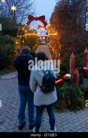 Una coppia che fotografa le luci e le decorazioni natalizie a Kittenberger Erlebnisgärten, una popolare destinazione turistica in Austria Foto Stock