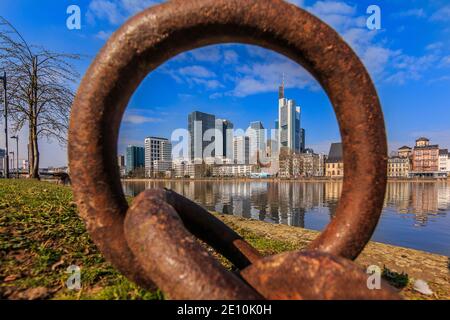 Alti edifici nel quartiere finanziario di Francoforte bloccati da un anello metallico. Parco lungo le rive del fiume meno in tempo soleggiato con blu Foto Stock