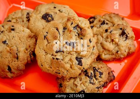 Gruppo di biscotti al cioccolato con chip su platter arancione in plastica, vista orizzontale Foto Stock