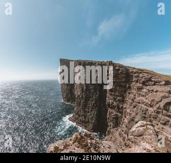 Faroe Islands Traelanipa la scogliera di roccia degli schiavi si vede innalzarsi sopra l'oceano vicino al lago Sorvagsvatn. Nuvole e cielo blu durante suommer sul Foto Stock