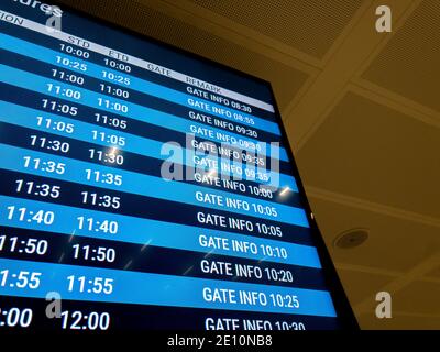 Uno schermo digitale blu in un aeroporto che annuncia l'ora e le informazioni del gate per ogni volo. Foto Stock