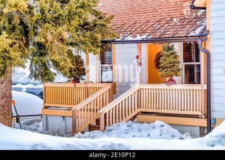 Home facciata tra enorme albero sempreverde e innevato nel paesaggio in inverno Foto Stock
