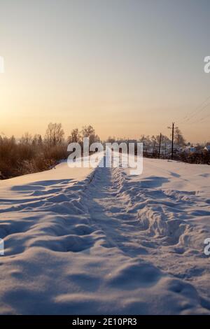 Una ferrovia coperta di neve e un sentiero calpestato dalle persone in inverno. Foto Stock