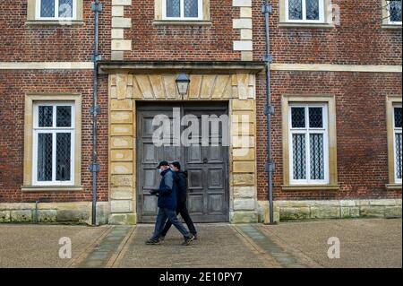 Eton, Windsor, Berkshire, Regno Unito. 3 gennaio 2021. Due uomini che indossano maschere facciali oltrepassano le porte chiuse all'ingresso della scuola pubblica Eton College, che ha chiuso all'inizio di dicembre a causa dei test degli studenti positivi per Covid-19. A seguito dell'enorme picco di casi positivi di Covid-19 nelle ultime settimane, molti insegnanti sono molto preoccupati per la sicurezza di riaprire le scuole dopo la pausa natalizia. Boris Johnson ha detto oggi che è sicuro per i bambini di tornare a scuola in aree dove sono in grado di. L'Associazione Nazionale dei Presidenti ha sollevato preoccupazioni con il governo circa la mancanza Foto Stock