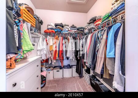 Vestiti all'interno di una cabina armadio di casa con moquette su pavimento  e parete bianca Foto stock - Alamy