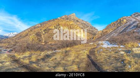 Paesaggio montano con terreno erboso in pendenza polverato con neve fresca in inverno Foto Stock