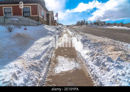 Percorso con piste da gommista lungo la strada in un quartiere innevato una giornata di sole in inverno Foto Stock