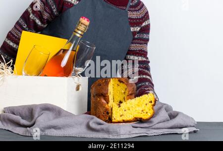 Mano femmina che tiene il panetone pasquale pezzo italiano vicino alla scatola di consegna con bottiglia di champagne. Foto Stock