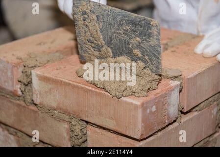 Muratore che lavora con la cazzuola di Smoothing alle pareti - Closeup Craftsman Foto Stock