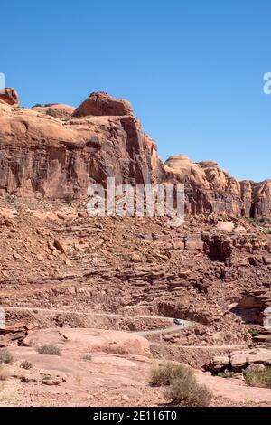 Un camion che guida lungo Kane Creek Road attraverso torreggianti rocce di arenaria rossa, Moab, Utah, USA Foto Stock